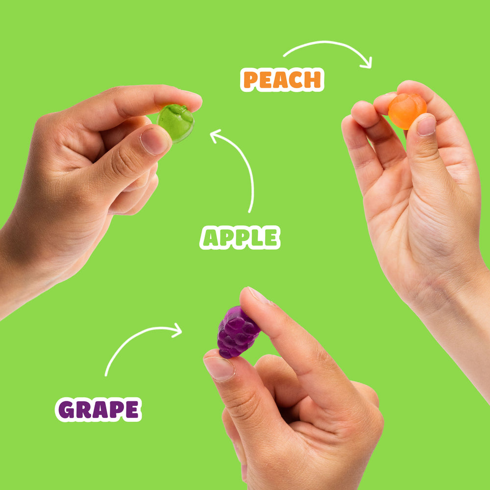 Hands holding fruit snacks labeled PEACH, APPLE, and GRAPE.